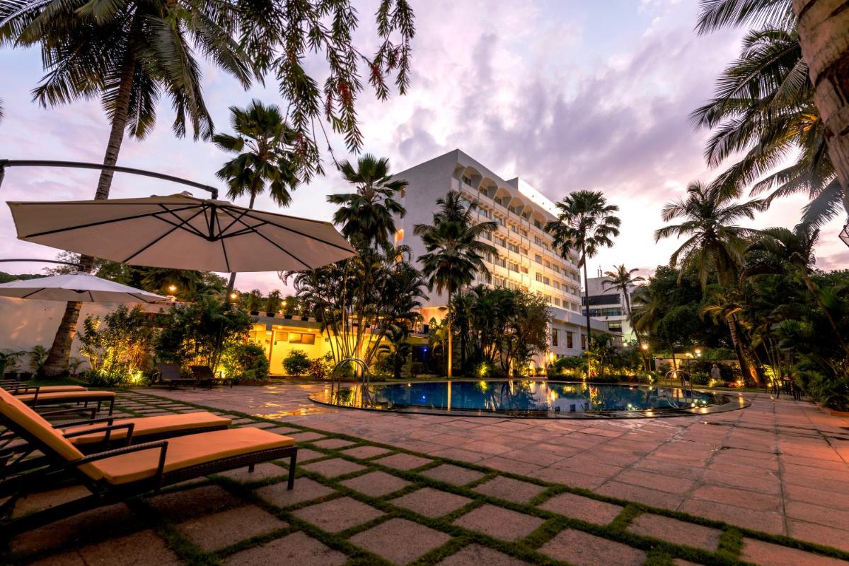 a resort pool with chairs and an umbrella and a building at Southern Star,Mysore in Mysore