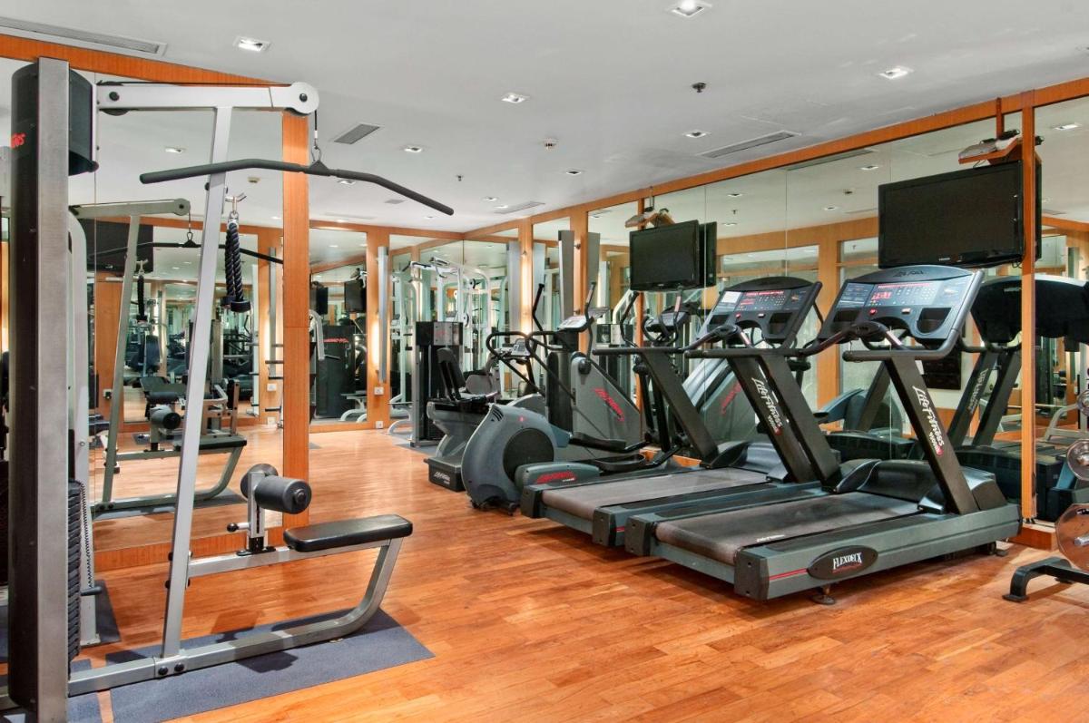 a gym with a row of treadmills and ellipticals at Hilton Mumbai International Airport Hotel in Mumbai