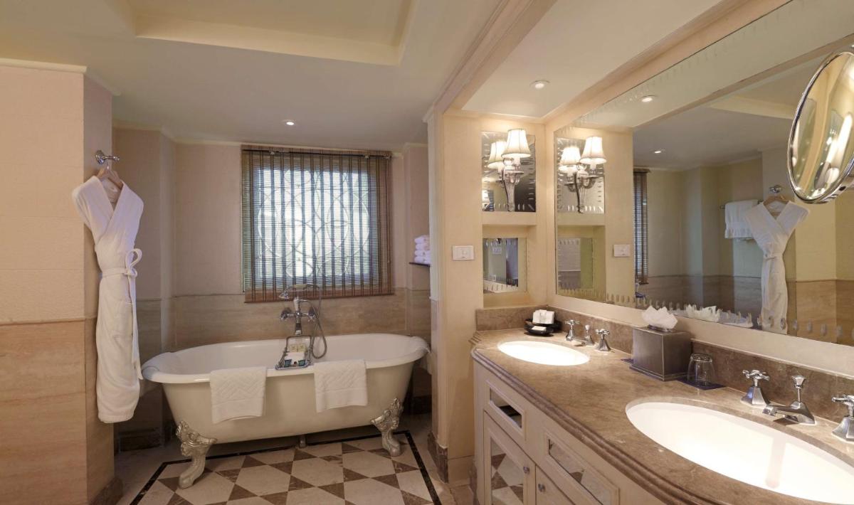 a bathroom with a tub and two sinks and a large mirror at Hilton Mumbai International Airport Hotel in Mumbai