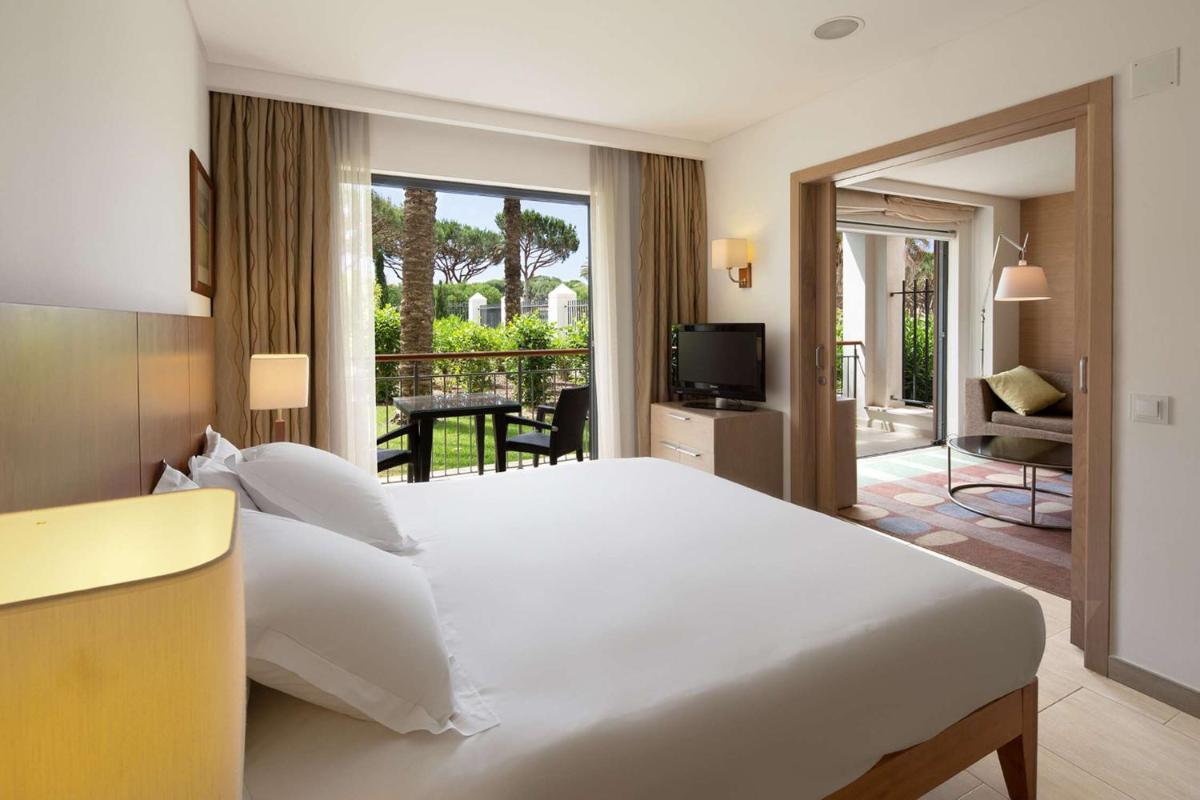 um quarto com uma grande cama branca e uma varanda em Hilton Vilamoura em Vilamoura