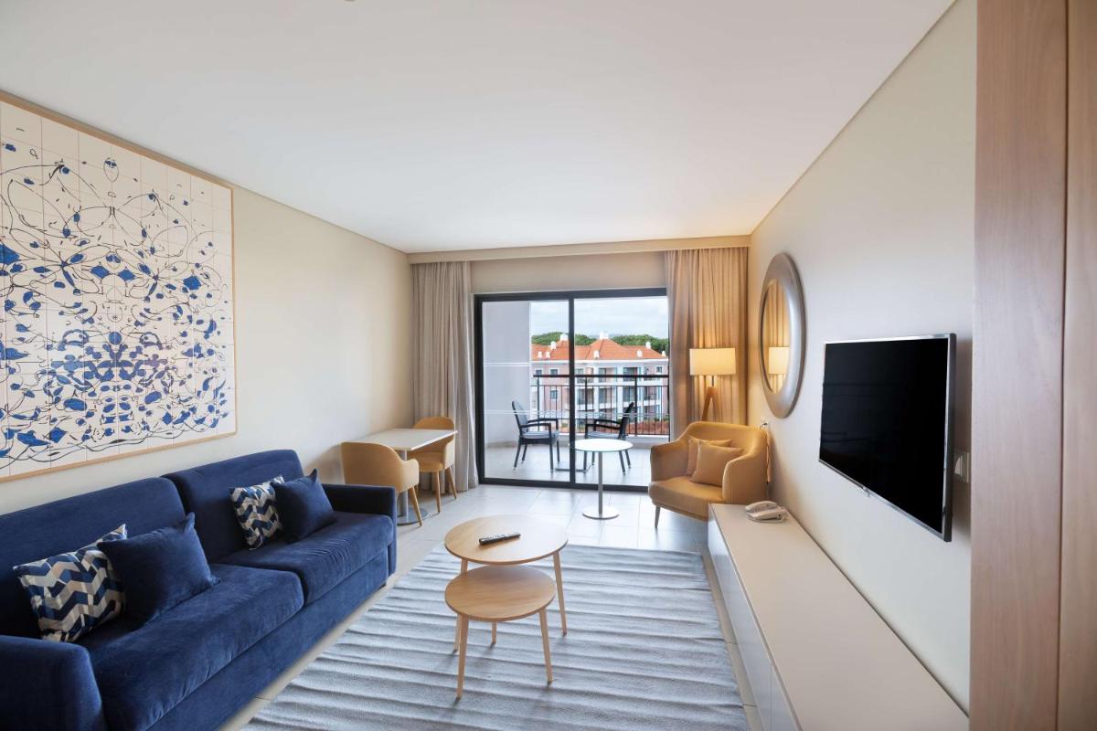 uma sala de estar com um sofá azul e uma TV em Hilton Vilamoura em Vilamoura