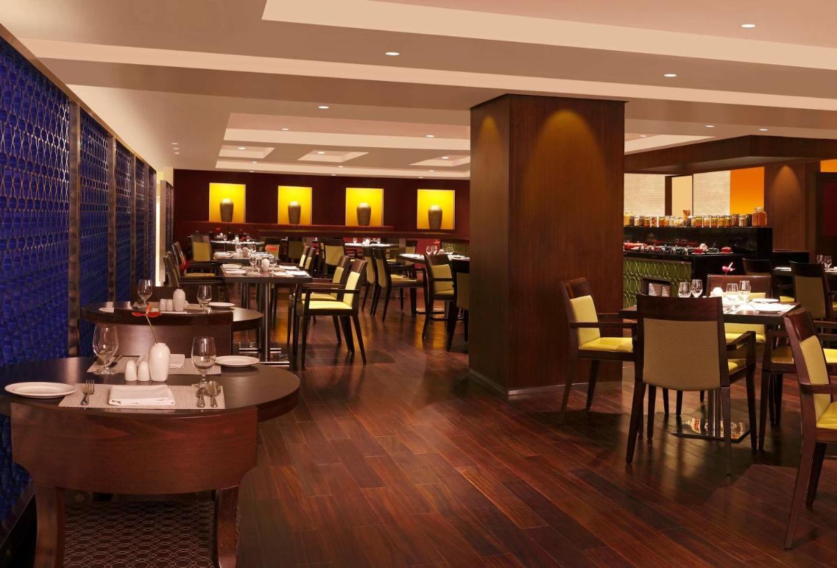 a restaurant with tables and chairs and a bar at Hilton Garden Inn, Trivandrum in Trivandrum