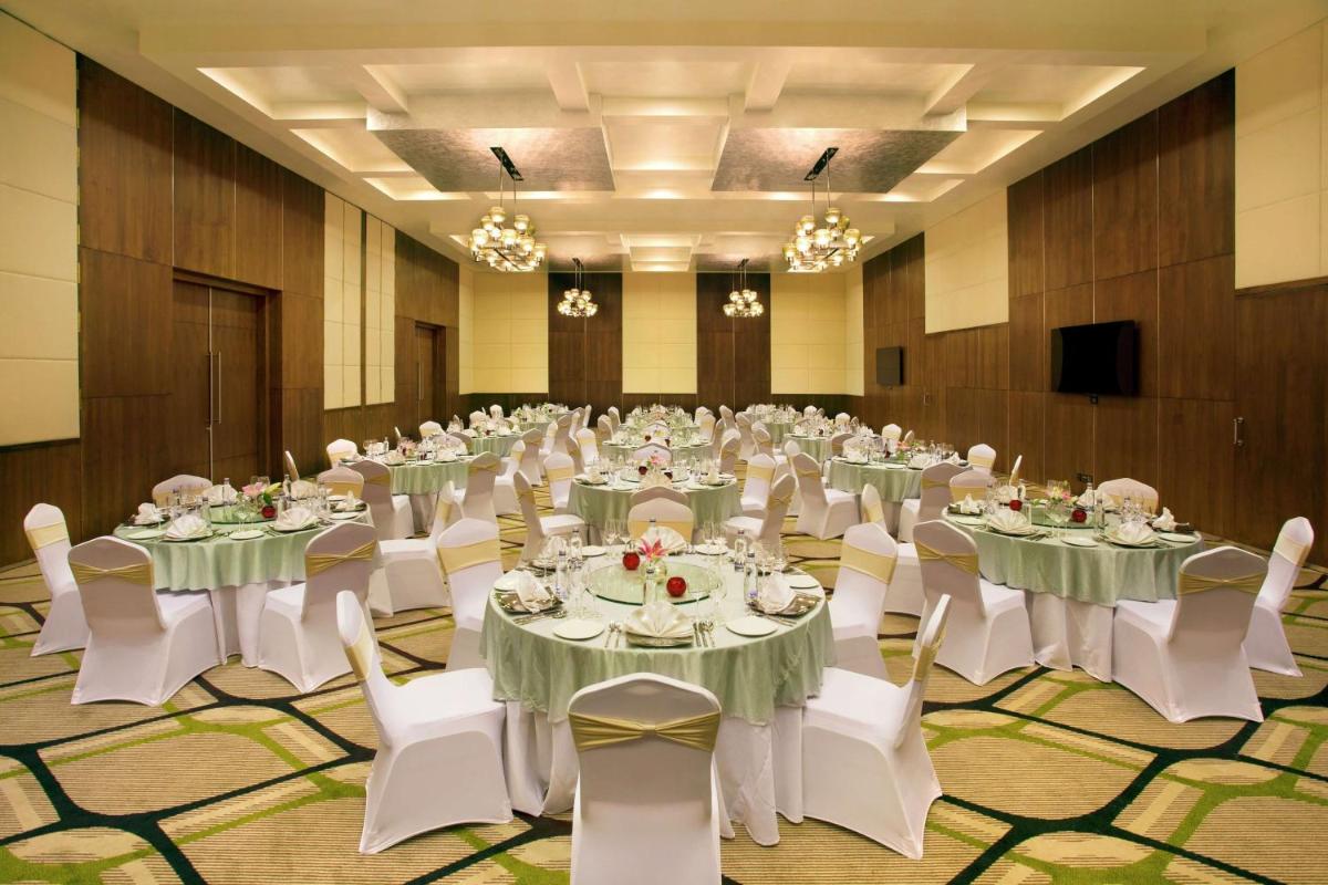 a large banquet hall with tables and white chairs at Hilton Garden Inn, Trivandrum in Trivandrum