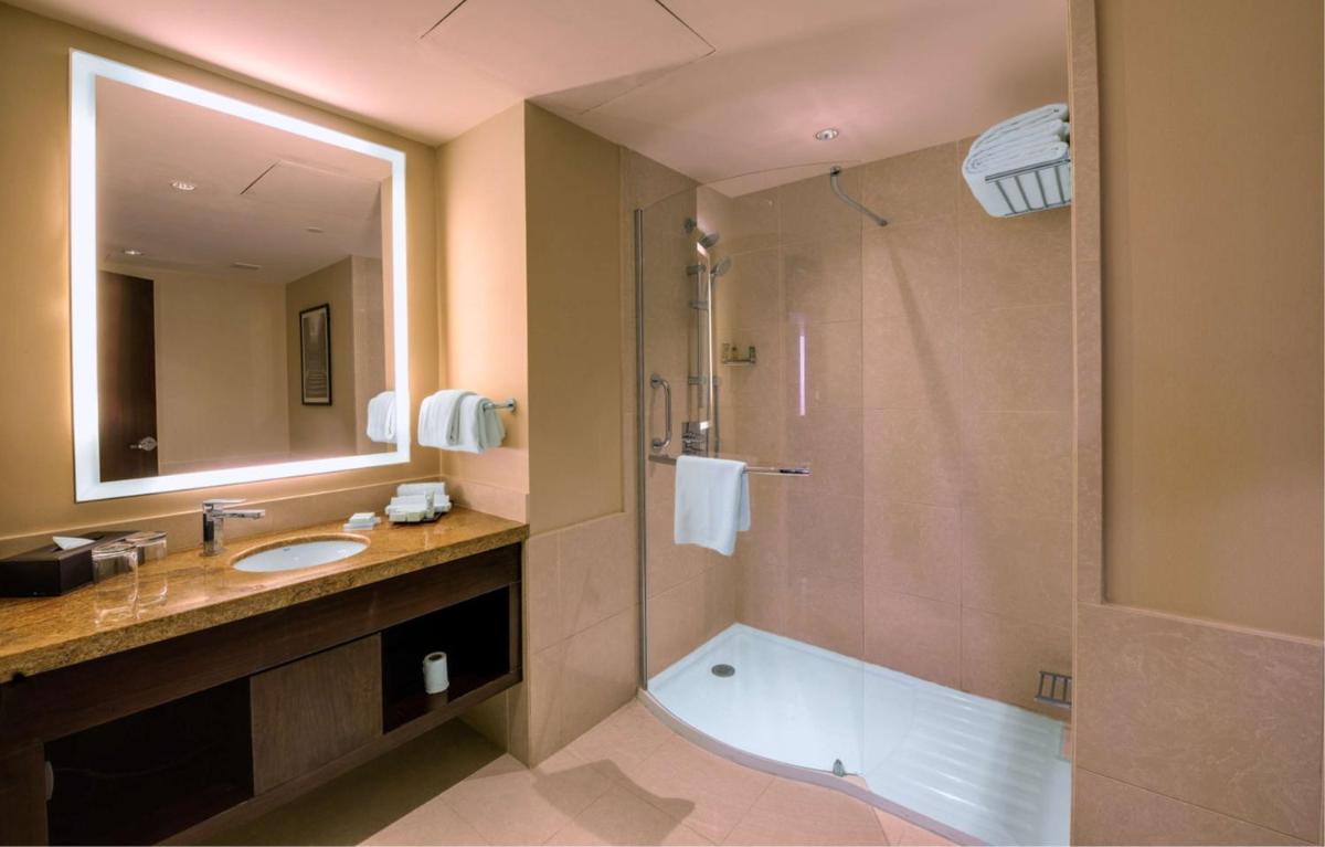 a bathroom with a shower and a sink and a tub at Hilton Garden Inn, Trivandrum in Trivandrum