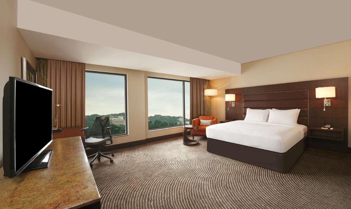 a hotel room with a bed and a flat screen tv at Hilton Garden Inn, Trivandrum in Trivandrum