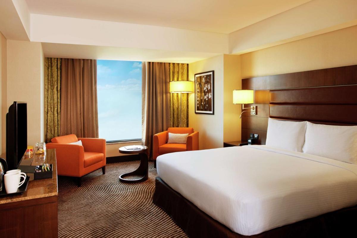 a hotel room with a bed and two chairs at Hilton Garden Inn, Trivandrum in Trivandrum