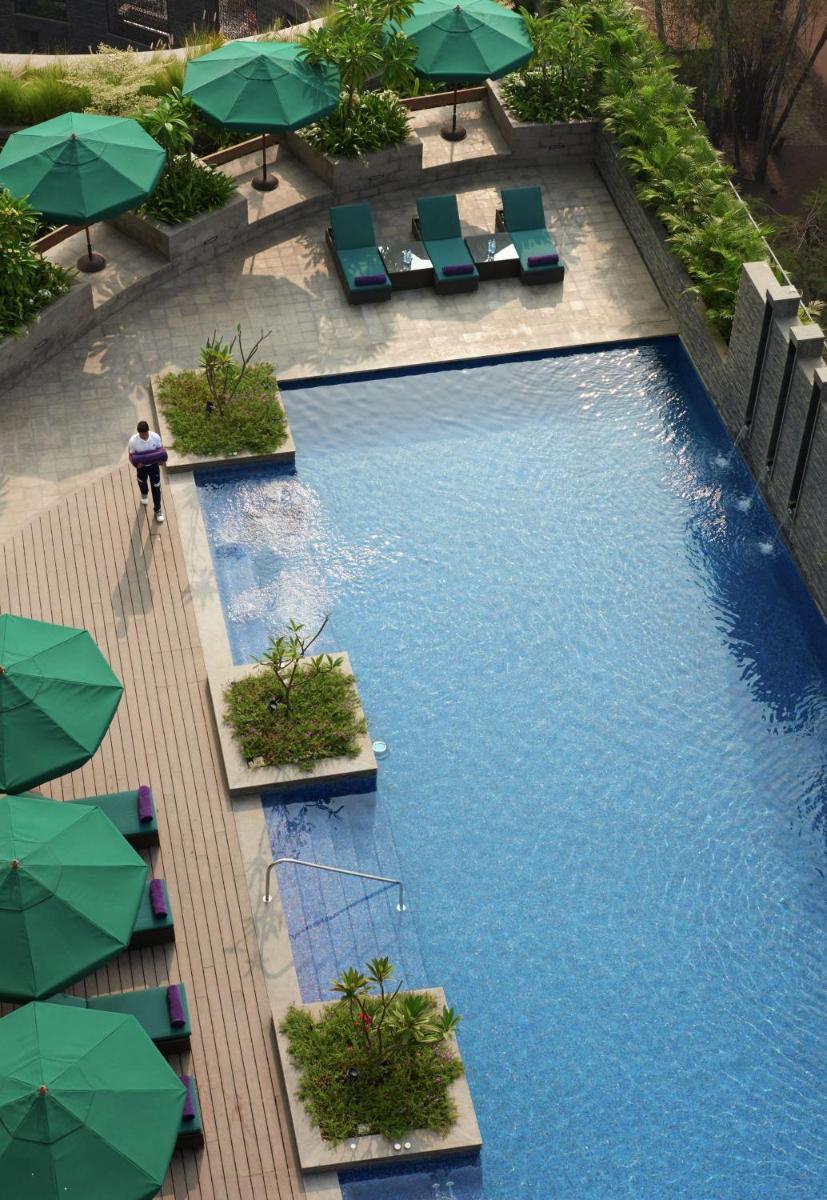 an overhead view of a pool with chairs and umbrellas at Conrad Pune in Pune