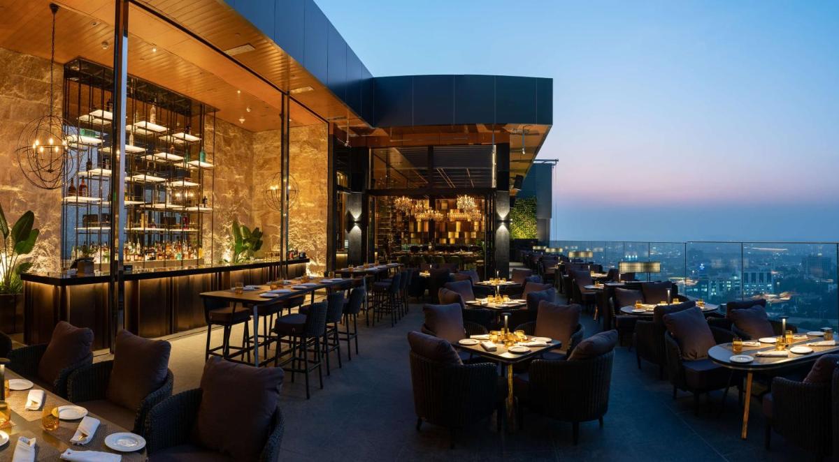 a restaurant with tables and chairs and a view at Conrad Pune in Pune