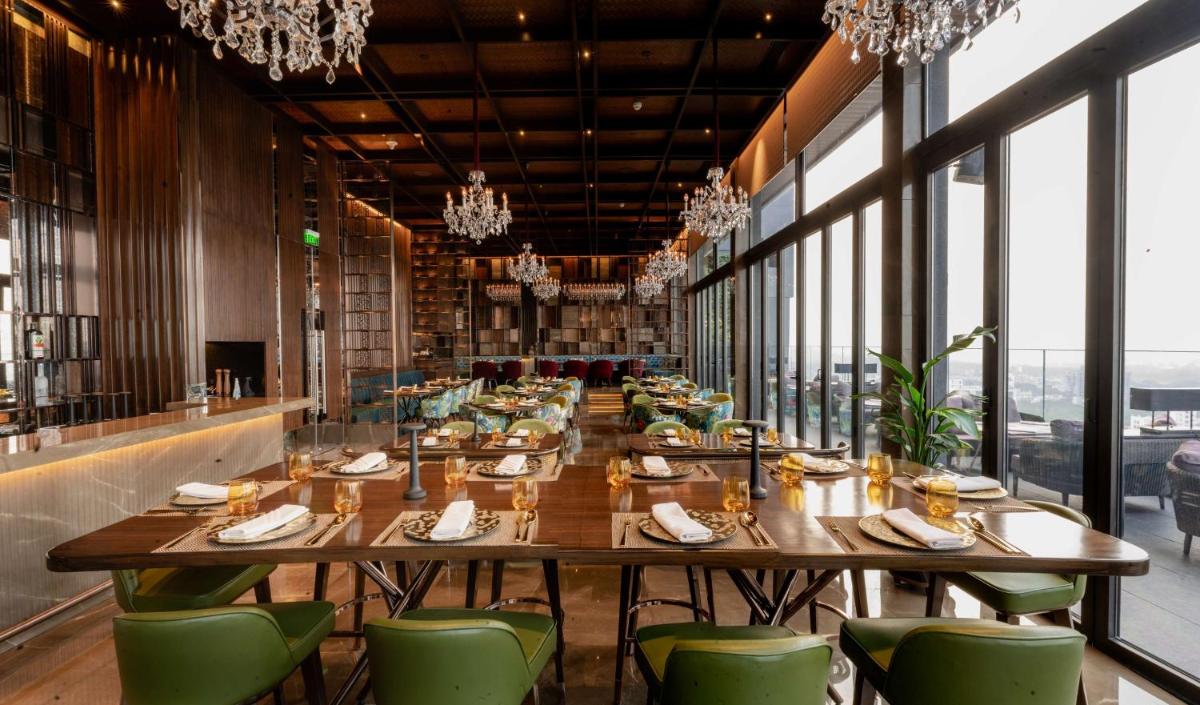 a dining room with long tables and green chairs at Conrad Pune in Pune
