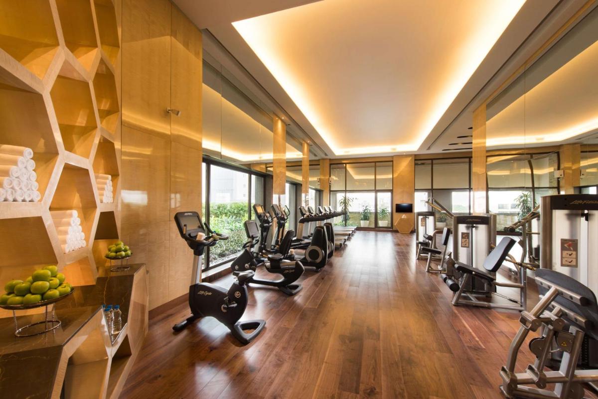 a gym with a row of treadmills and ellipticals at Conrad Pune in Pune