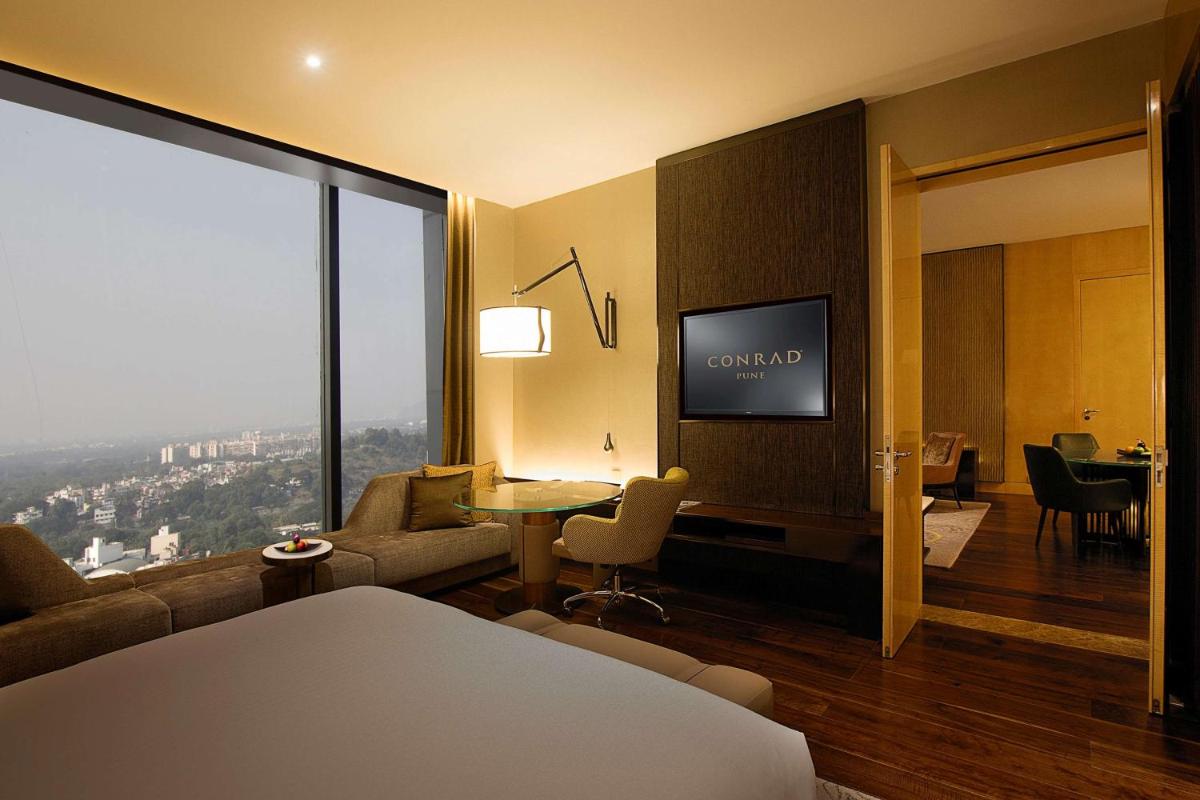 a hotel room with a bed and a living room at Conrad Pune in Pune