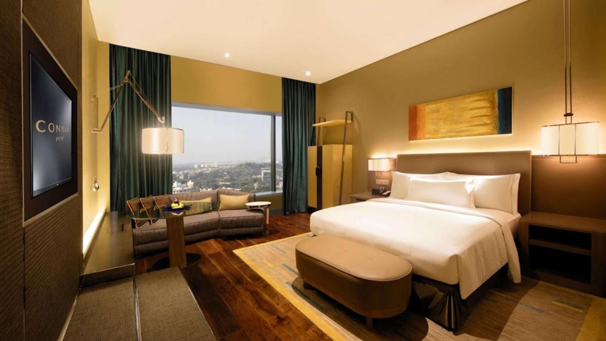 a hotel room with a bed and a tv at Conrad Pune in Pune
