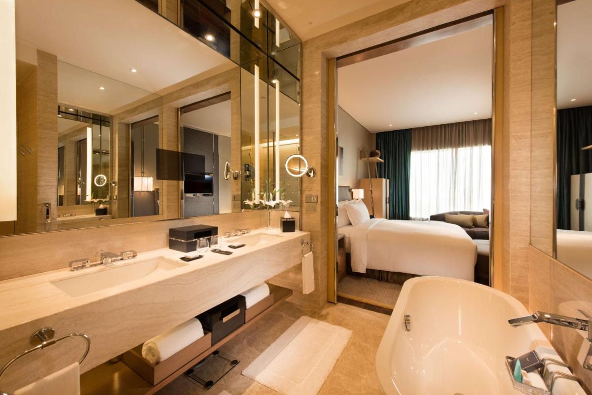 a bathroom with a bed and a sink and a tub at Conrad Pune in Pune