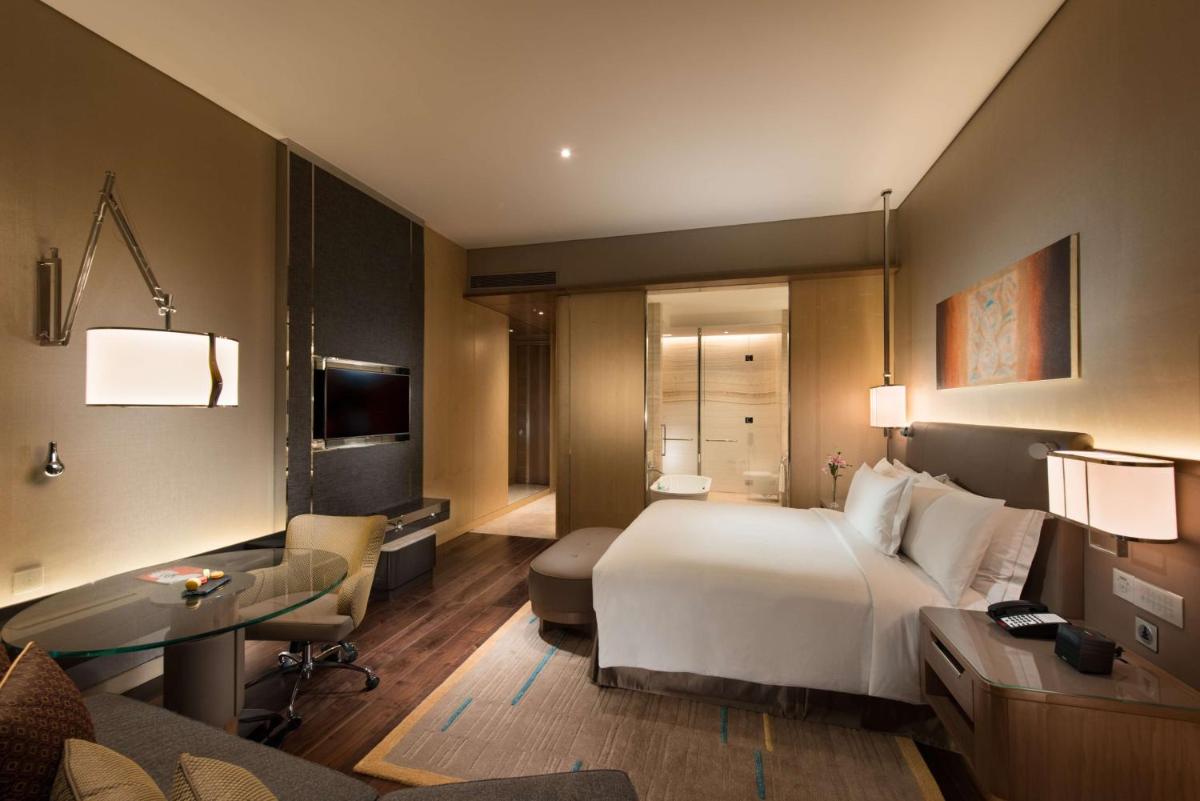 a hotel room with a bed and a desk and a couch at Conrad Pune in Pune