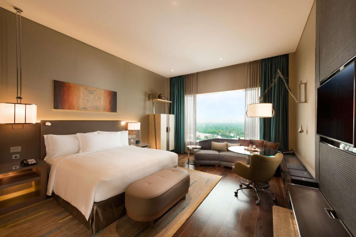 a hotel room with a large bed and a desk at Conrad Pune in Pune