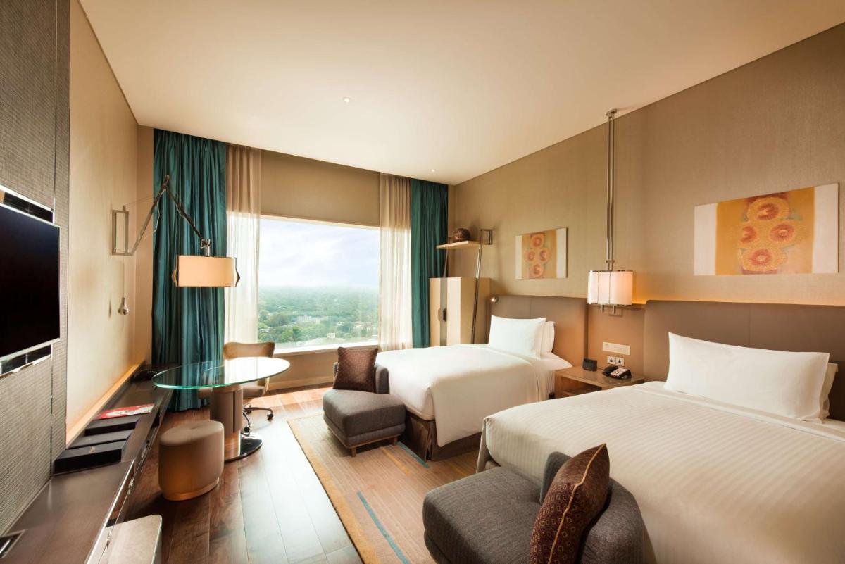 a hotel room with two beds and a television at Conrad Pune in Pune