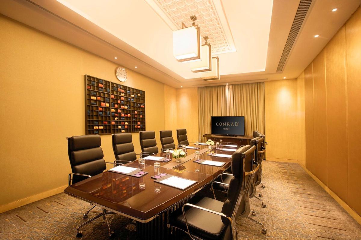 a conference room with a long table and chairs at Conrad Pune in Pune
