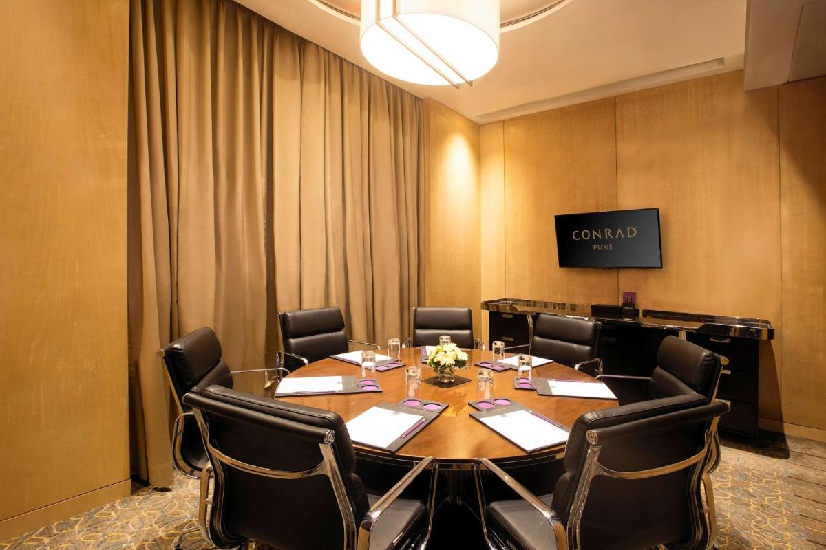 a conference room with a large table and chairs at Conrad Pune in Pune