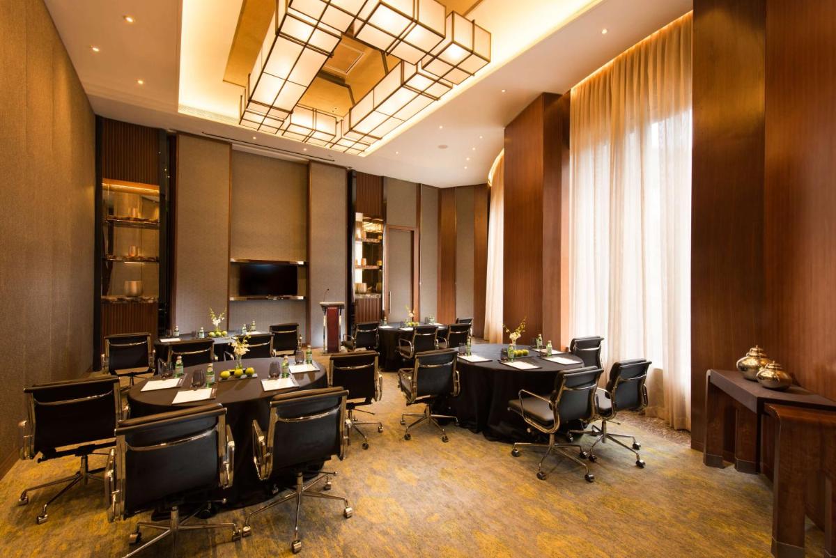 a conference room with tables and chairs and a chandelier at Conrad Pune in Pune