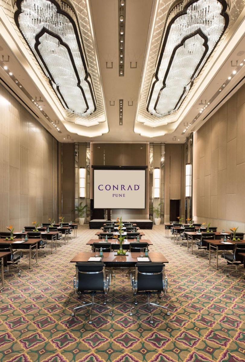 a conference room with tables and a screen at Conrad Pune in Pune