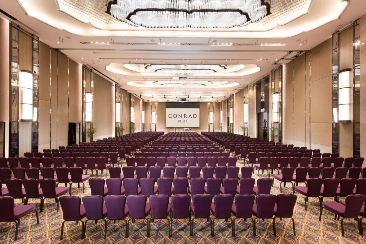 an empty hall with purple chairs and a stage at Conrad Pune in Pune