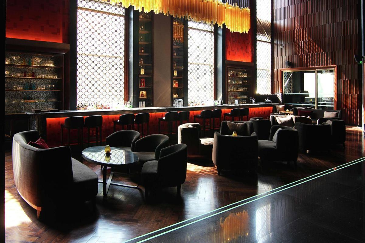 a restaurant with a bar with chairs and a table at Conrad Pune in Pune