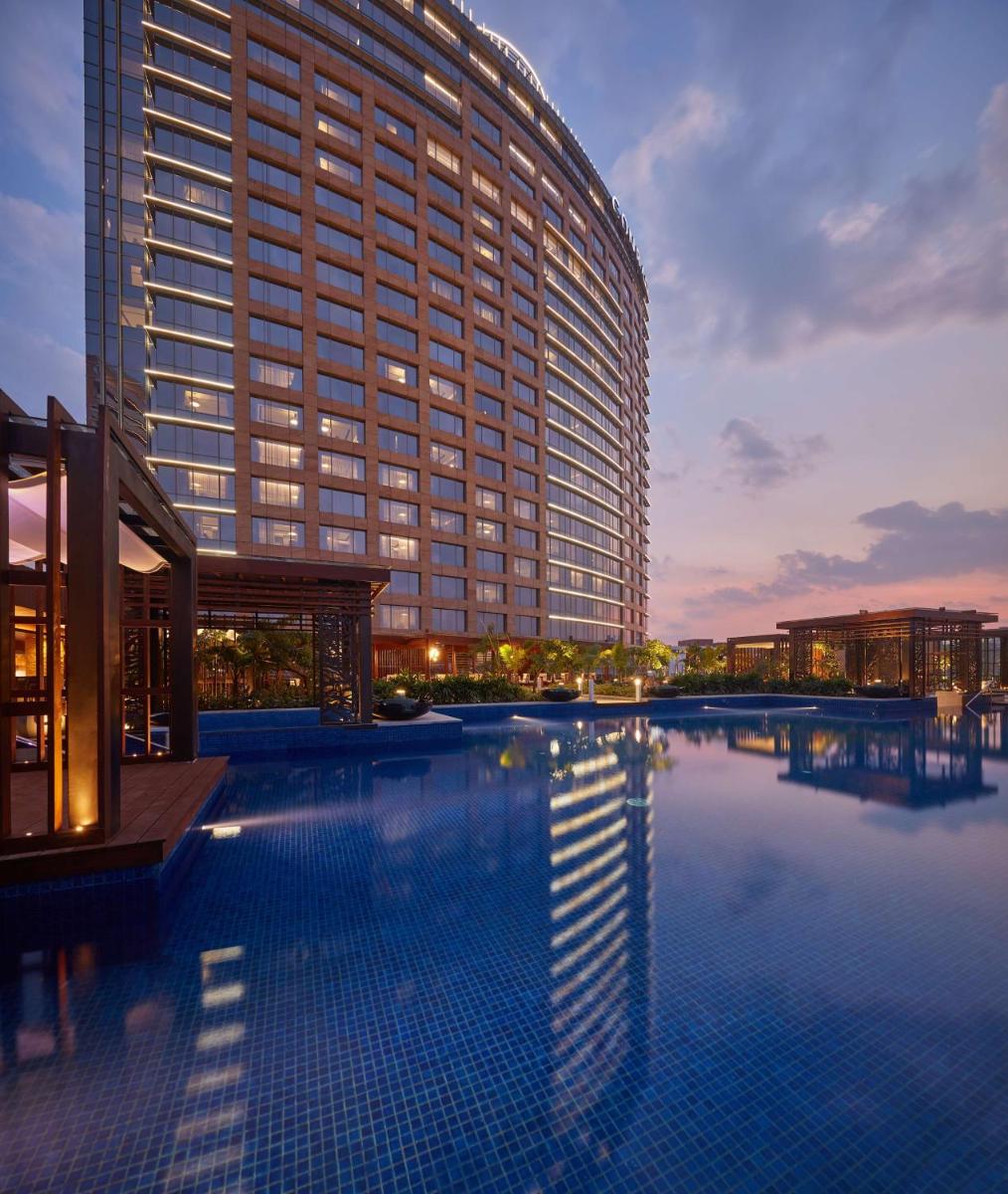 a large building with a swimming pool in front of it at Conrad Bengaluru in Bengaluru a large building with a swimming pool in front of it at Conrad Bengaluru in Bengaluru
