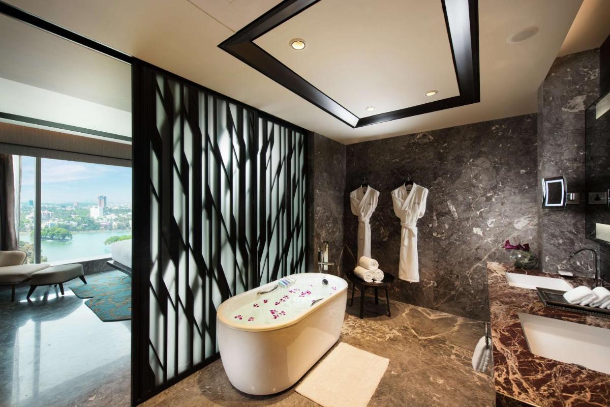 a bathroom with a bath tub and a sink at Conrad Bengaluru in Bengaluru a bathroom with a bath tub and a sink at Conrad Bengaluru in Bengaluru