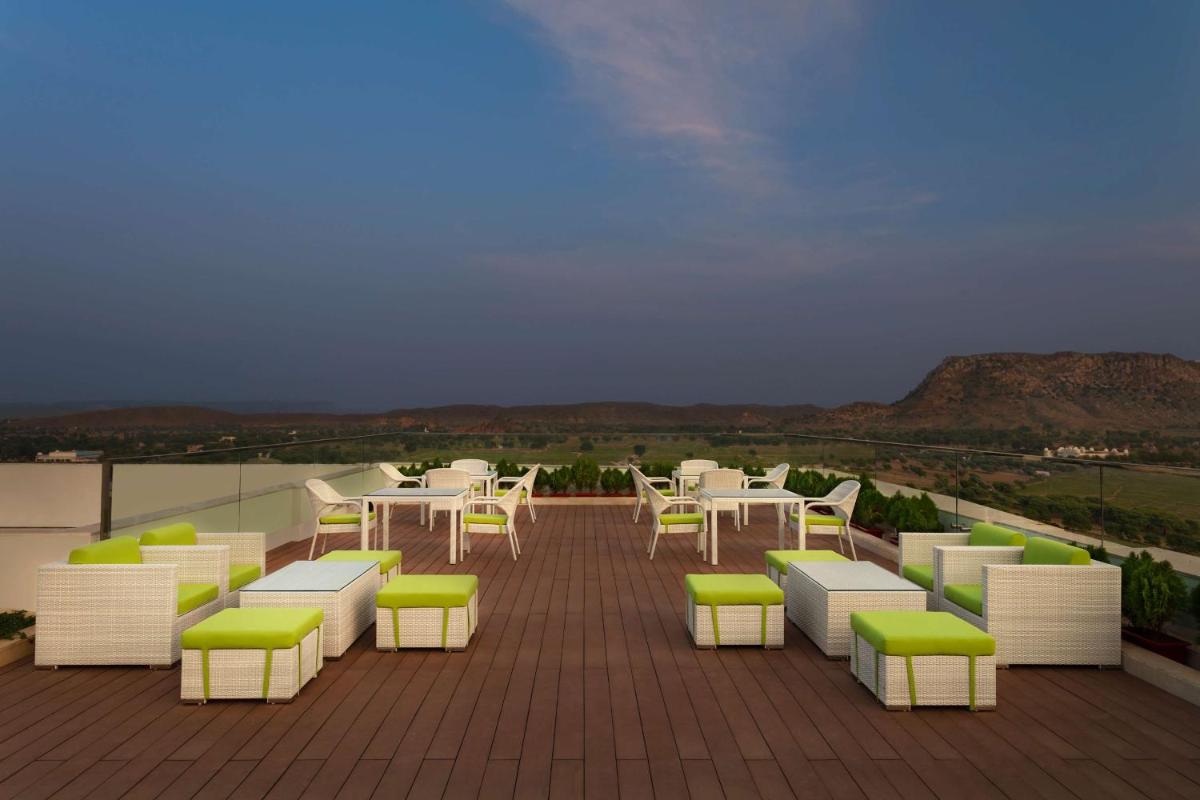 a patio with white tables and green and white chairs at DoubleTree By Hilton Jaipur Amer in Jaipur