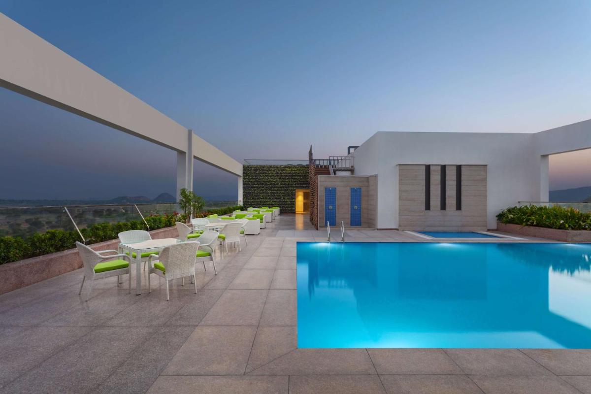 a pool on the roof of a building with tables and chairs at DoubleTree By Hilton Jaipur Amer in Jaipur a pool on the roof of a building with tables and chairs at DoubleTree By Hilton Jaipur Amer in Jaipur