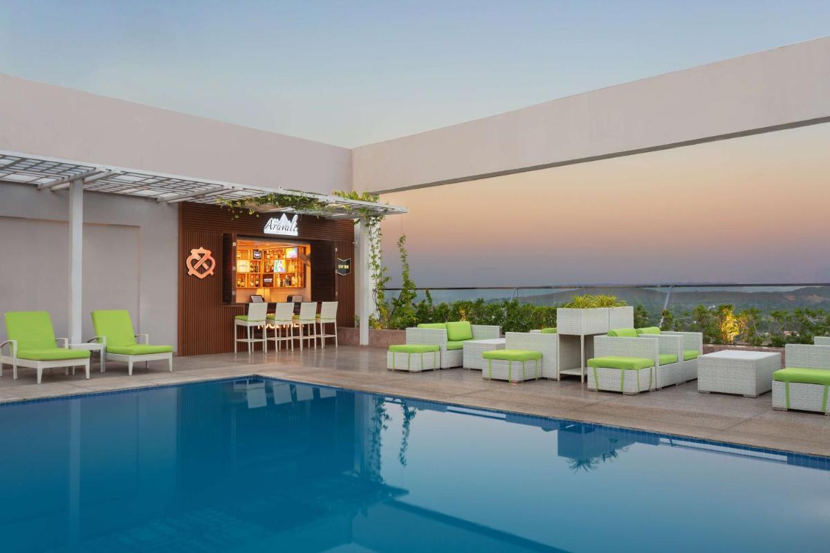 a pool with green and white chairs and a bar at DoubleTree By Hilton Jaipur Amer in Jaipur