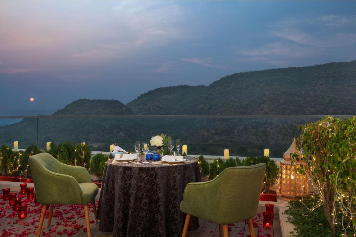 a dining table with chairs and a view of mountains at DoubleTree By Hilton Jaipur Amer in Jaipur