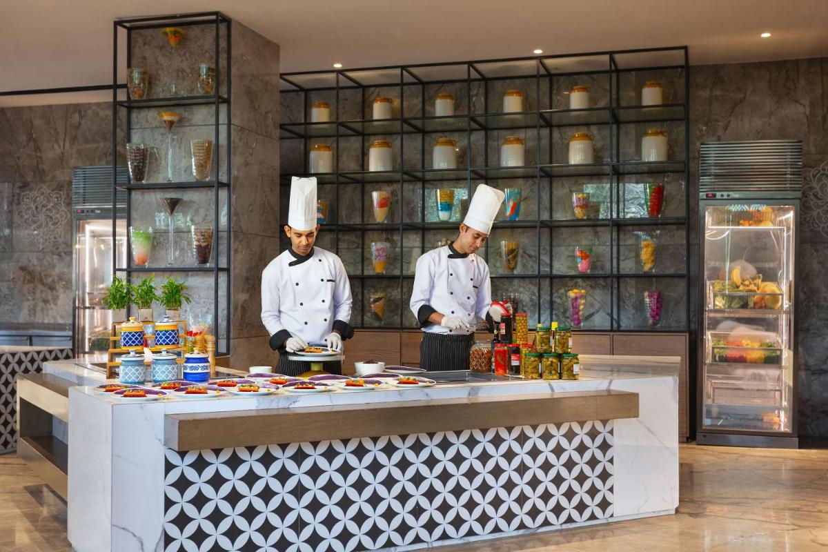 two chefs standing in a kitchen preparing food at DoubleTree By Hilton Jaipur Amer in Jaipur
