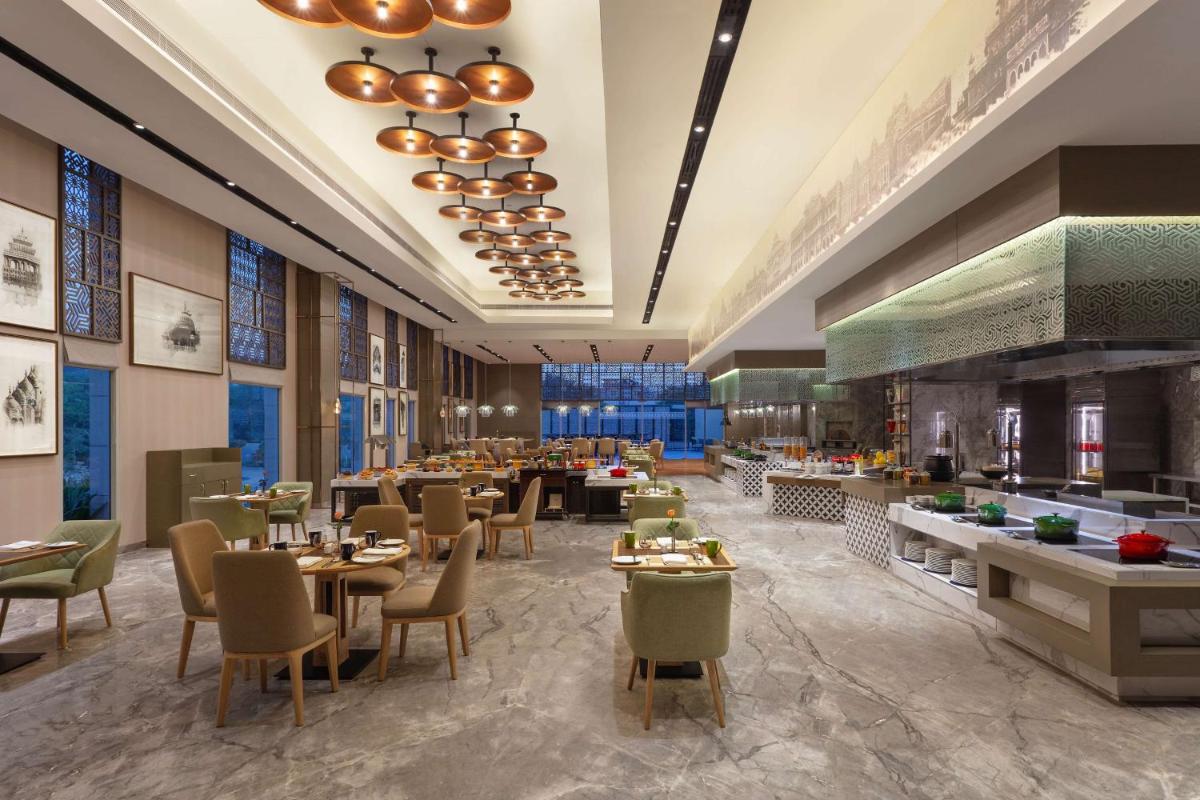 a restaurant with tables and chairs in a room at DoubleTree By Hilton Jaipur Amer in Jaipur a restaurant with tables and chairs in a room at DoubleTree By Hilton Jaipur Amer in Jaipur