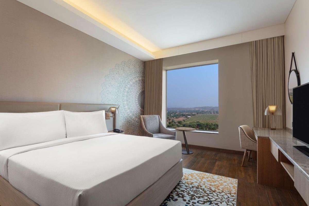a bedroom with a bed and a large window at DoubleTree By Hilton Jaipur Amer in Jaipur