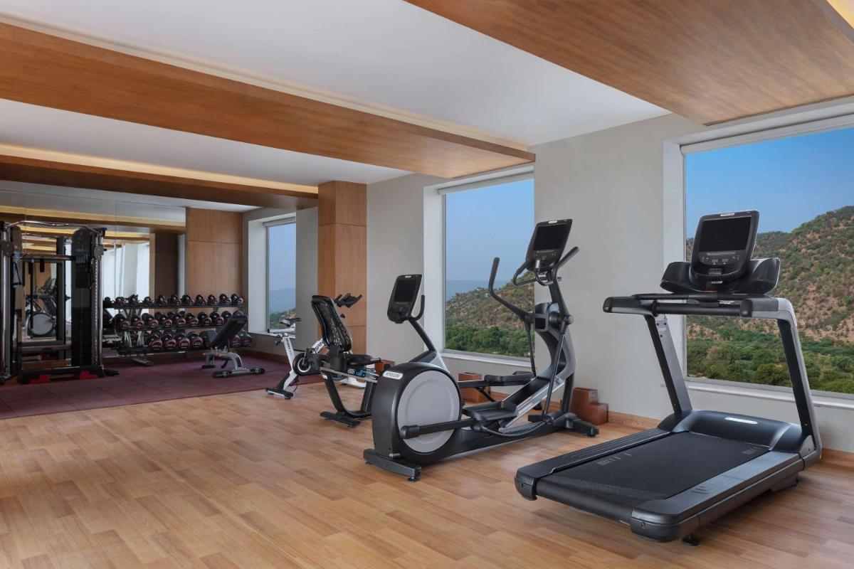 a gym with treadmills and exercise equipment and windows at DoubleTree By Hilton Jaipur Amer in Jaipur