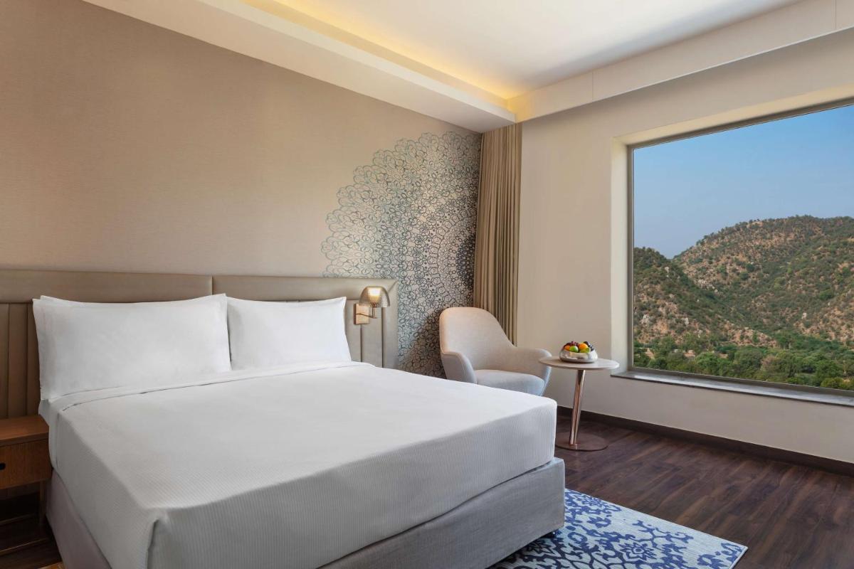 a bedroom with a large bed and a large window at DoubleTree By Hilton Jaipur Amer in Jaipur