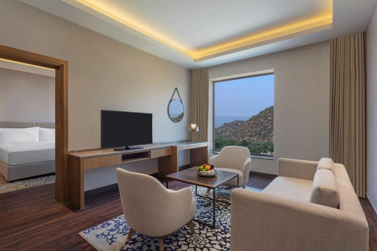 a hotel room with a living area with a television and a bed at DoubleTree By Hilton Jaipur Amer in Jaipur