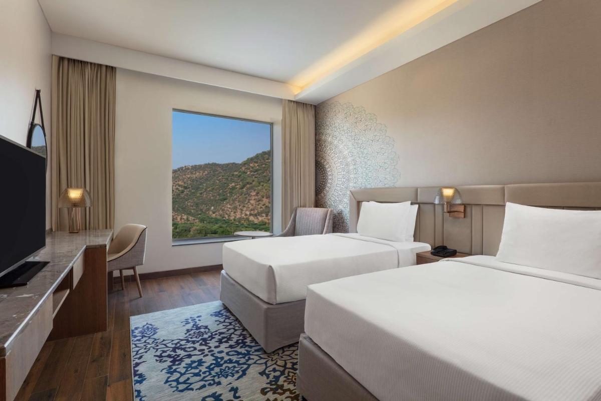 a hotel room with two beds and a large window at DoubleTree By Hilton Jaipur Amer in Jaipur