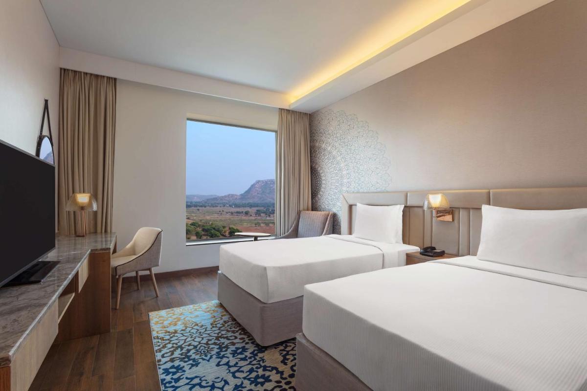 a hotel room with two beds and a large window at DoubleTree By Hilton Jaipur Amer in Jaipur a hotel room with two beds and a large window at DoubleTree By Hilton Jaipur Amer in Jaipur