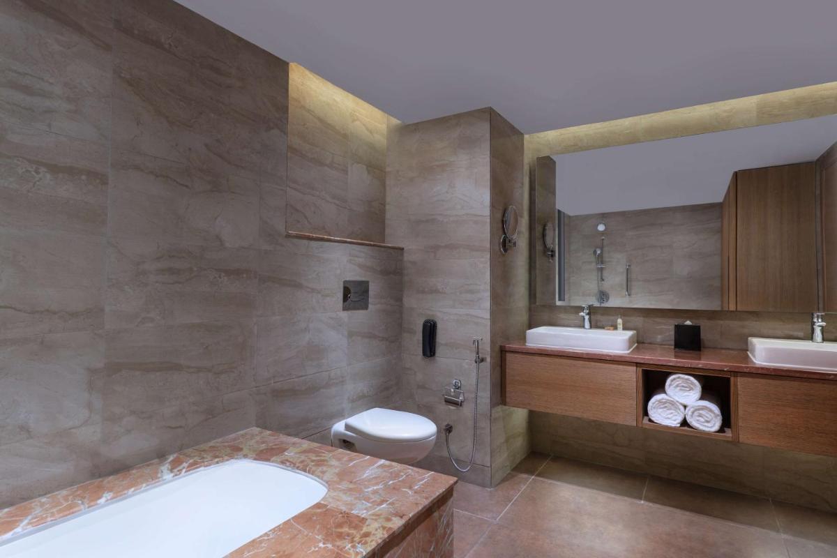 a bathroom with a tub and a toilet and a sink at DoubleTree By Hilton Jaipur Amer in Jaipur