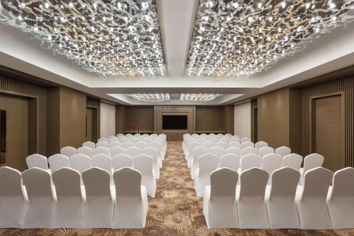 a conference room with white chairs and a screen at DoubleTree By Hilton Jaipur Amer in Jaipur