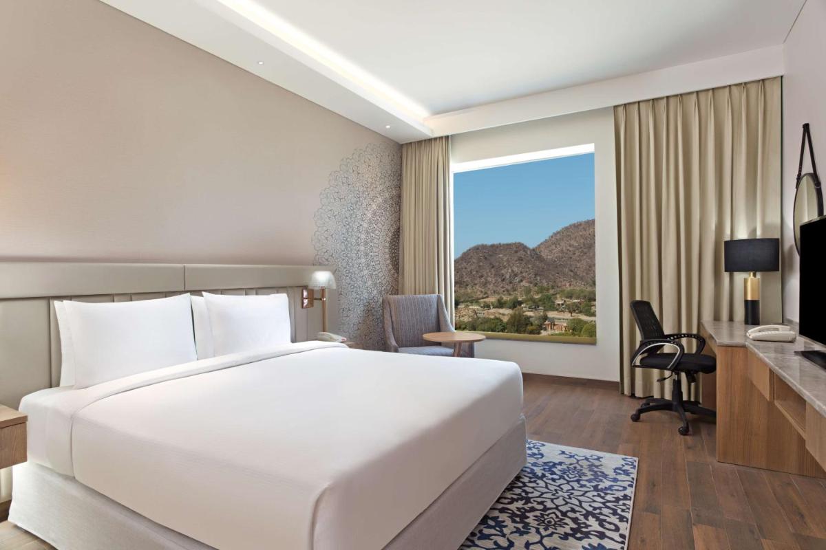 a hotel room with a large white bed and a window at DoubleTree By Hilton Jaipur Amer in Jaipur