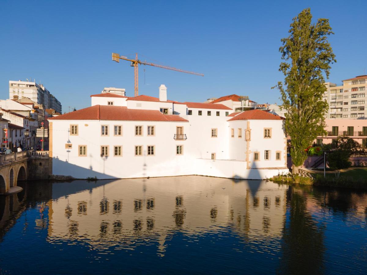 um edifício branco sentado na água ao lado de edifícios em Vila Gale Collection Tomar em Tomar