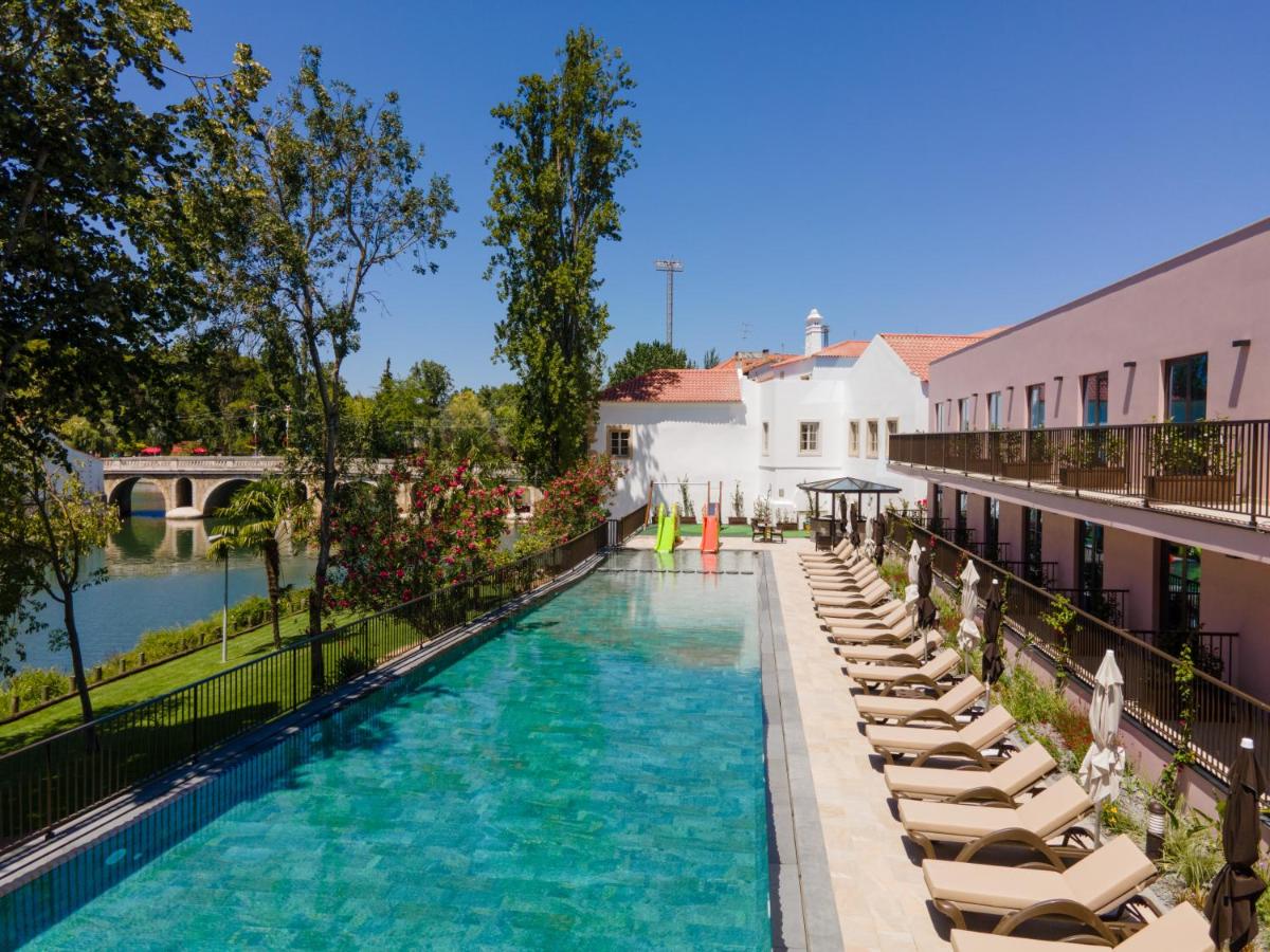 uma piscina com espreguiçadeiras e um resort em Vila Gale Collection Tomar em Tomar