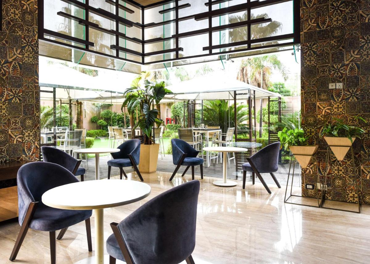 a restaurant with tables and chairs and plants at DoubleTree by Hilton Gurugram Baani Square in Gurgaon
