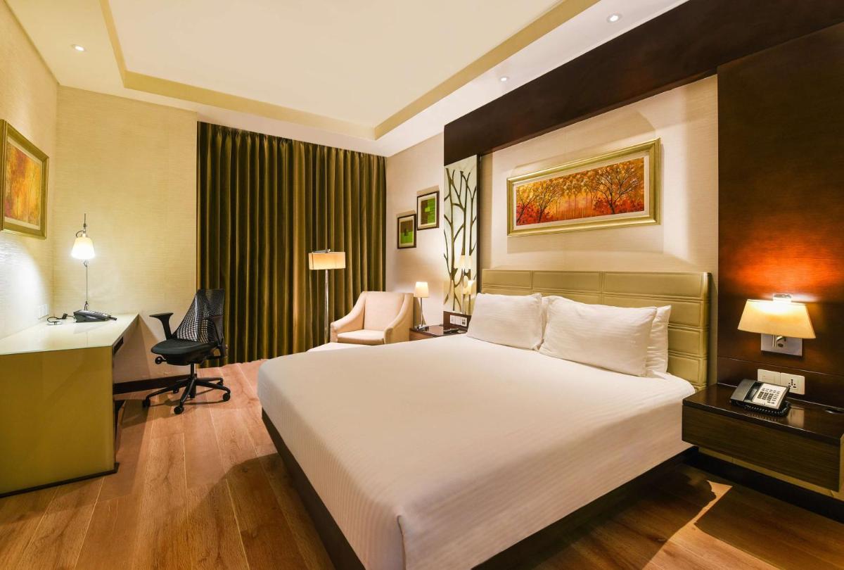 a hotel room with a large bed and a desk at DoubleTree by Hilton Gurugram Baani Square in Gurgaon