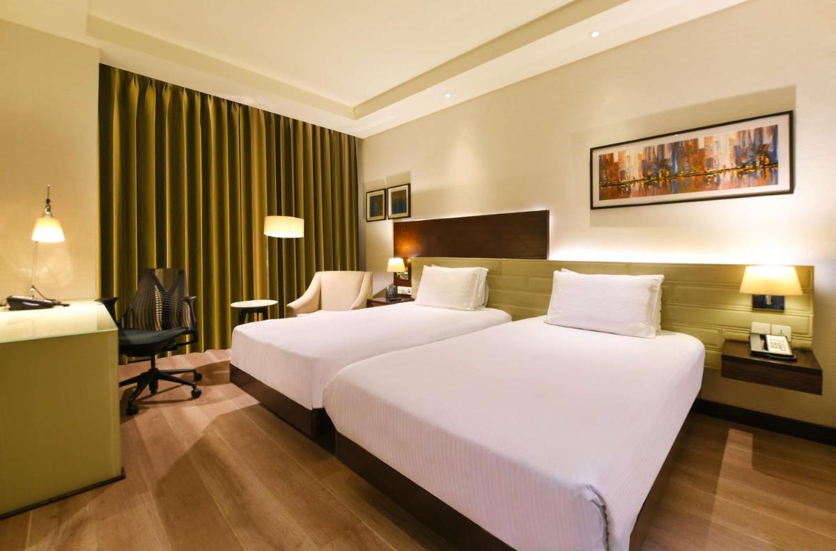 a hotel room with two beds and a desk at DoubleTree by Hilton Gurugram Baani Square in Gurgaon