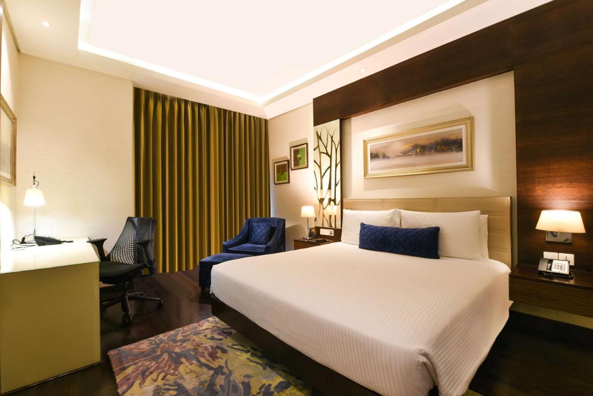 a hotel room with a bed and a desk and chair at DoubleTree by Hilton Gurugram Baani Square in Gurgaon