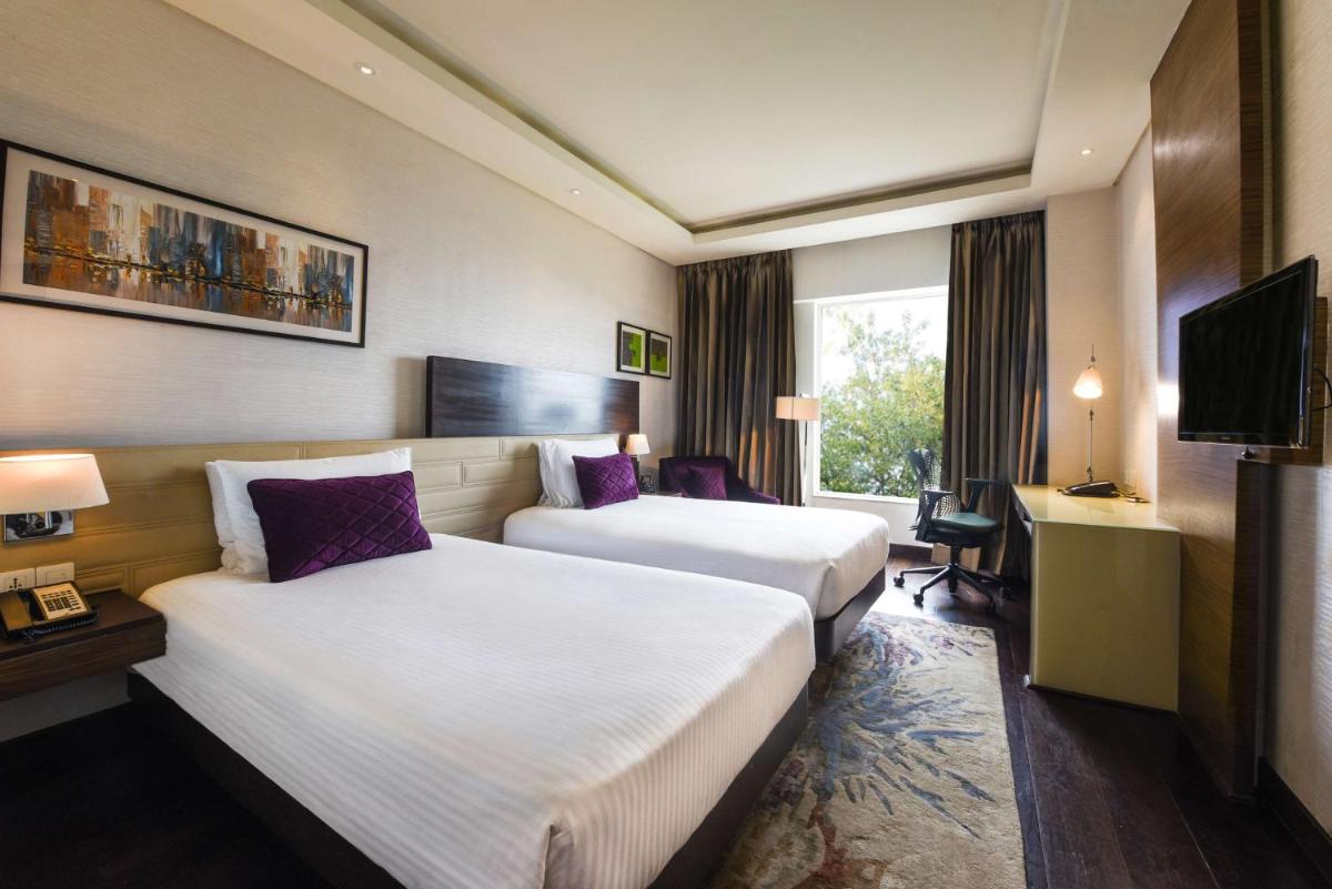 a hotel room with two beds and a television at DoubleTree by Hilton Gurugram Baani Square in Gurgaon